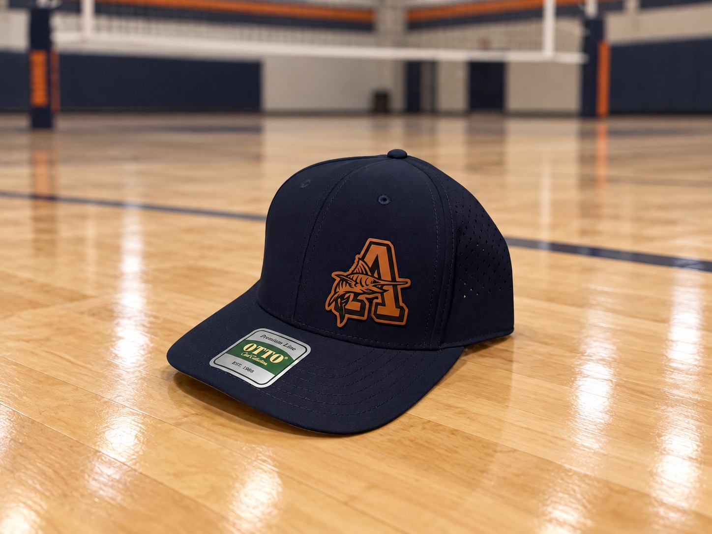 Solid navy Arnold High School hat with an orange A and marlin patch on an indoor volleyball court.